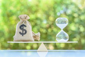 Time value of money, asset growth over time, financial concept : Dollar bags, sand clock or hourglass on a balance scale in equal position, depicts investment in long-term equity for more money growth