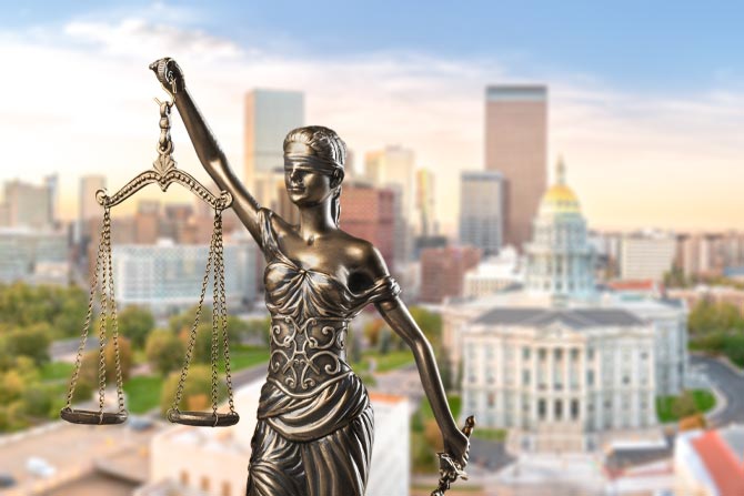 Fair Lending in 2026; Statue of Lady Justice holding scales, set against a blurred cityscape backdrop with tall buildings and a classical domed structure under a clear sky.