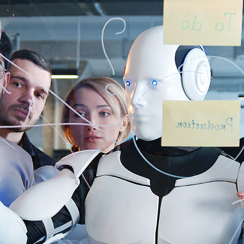 From-Scramble-to-Strategy-FEATURE - AI robot writing on a clear board with lots of humans standing around observing.