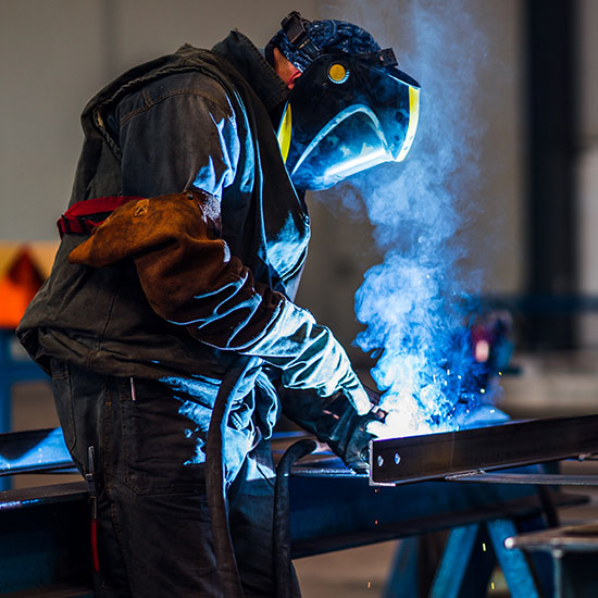 How-Lenders-Can-FEATURE - Man welding a steel frame together wearing a welders mask.