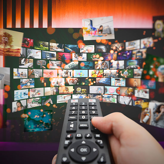 When-More-Choice-FEATURE - hand holding a remote and having to choose between lots of screens for choice of what to watch.